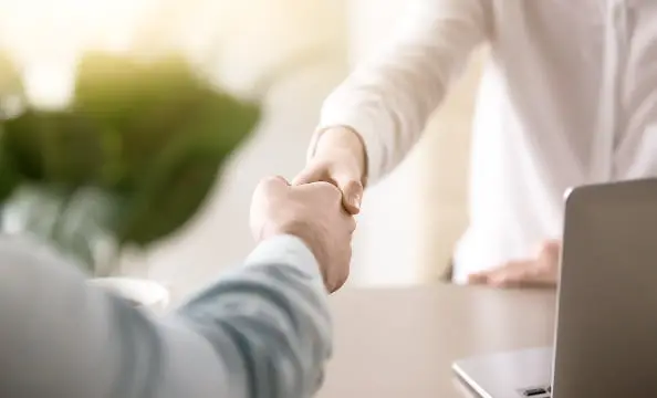 明るい空間で二人の人物が握手をしている様子。